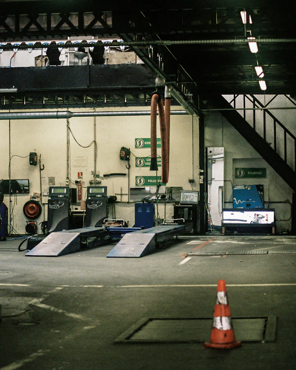 An MOT bay with two drive-on ramps, a brake tester and a traffic cone on the floor