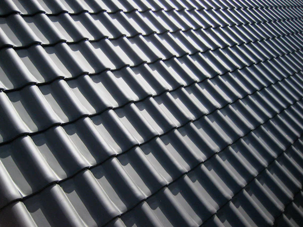 New dark grey interlocking roof tiles in hard sunlight