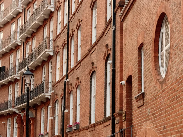 Tall red brick houses with iron balconies along a paved street