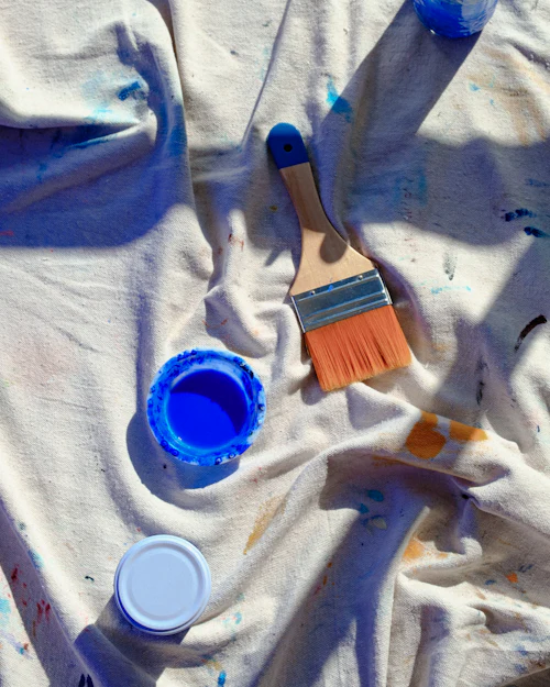Brushes and open paint pots on a crumpled dust sheet
