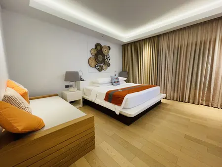 A bedroom with white linen and a tall window.