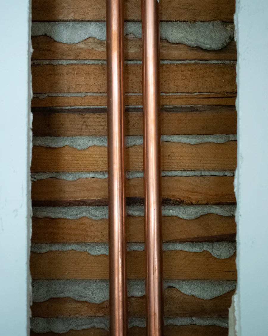 Two copper pipes run straight and parallel in a channel cut into a brick wall