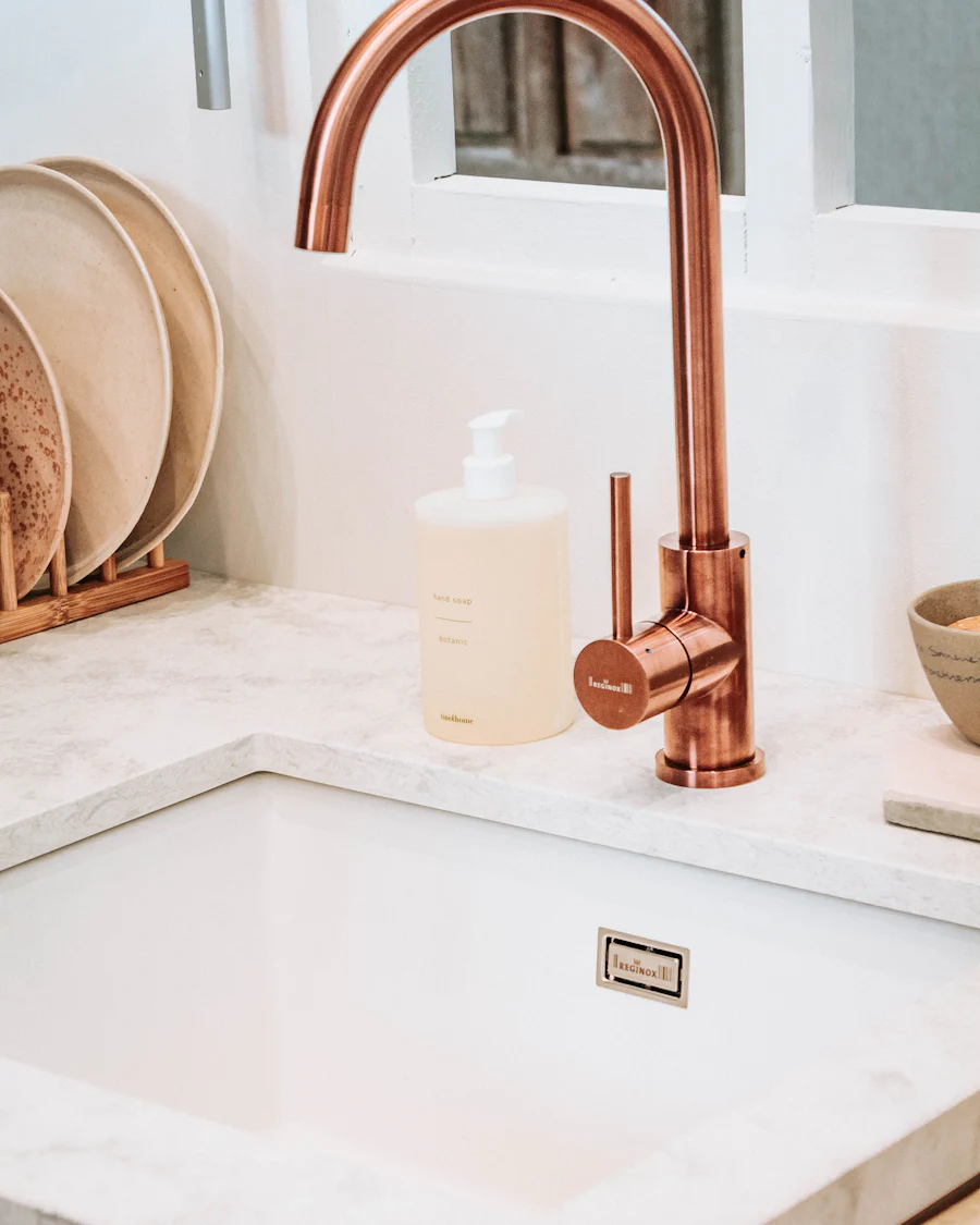 A copper kitchen tap over a square white sink