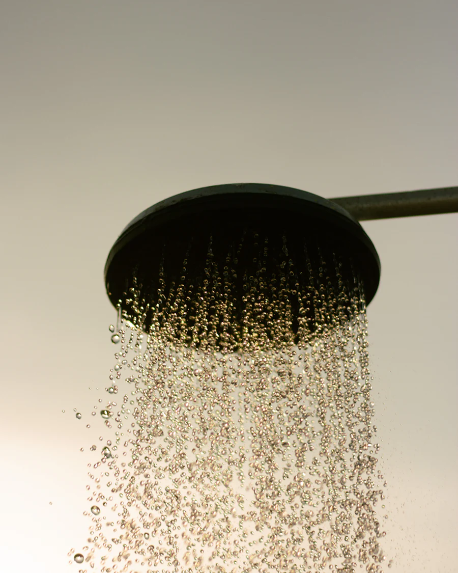 A round rainfall shower head with water falling from it