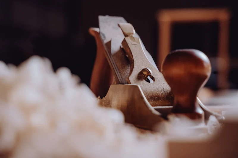 A metal hand plane with a wooden knob resting in a drift of pale shavings