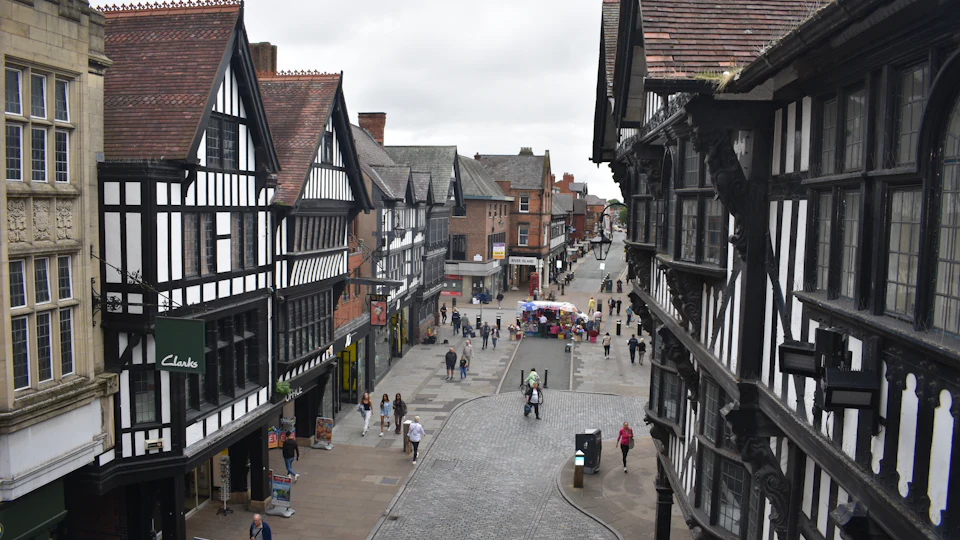 Looking down a long shopping street of black-and-white timbered buildings with covered galleries on both sides