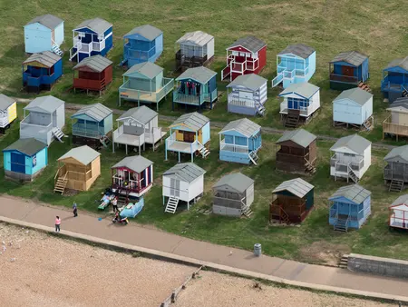 Rows of painted beach huts on the grass above the shingle at Tankerton.