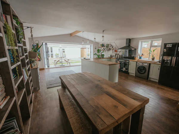 A long kitchen-diner with a rustic oak table and benches, the kitchen at the far end