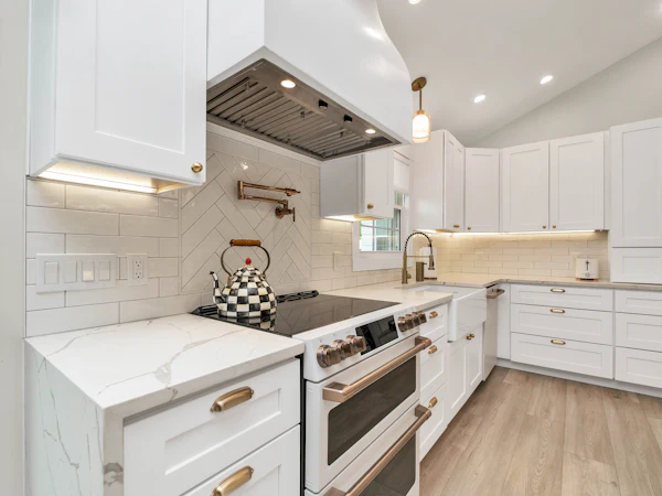 White shaker units with a white quartz worktop and a matching upstand behind the hob
