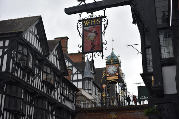 Chester’s Eastgate clock on the city walls between black and white buildings