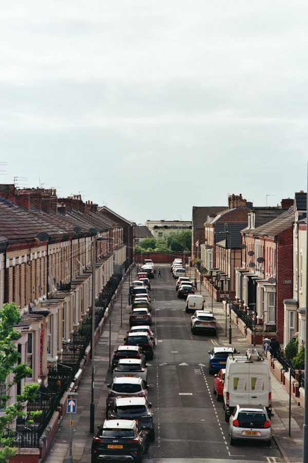 A long street of red-brick terraced houses with cars parked down both sides