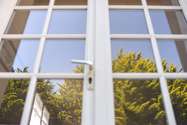 A white uPVC window frame with a locking handle, trees outside