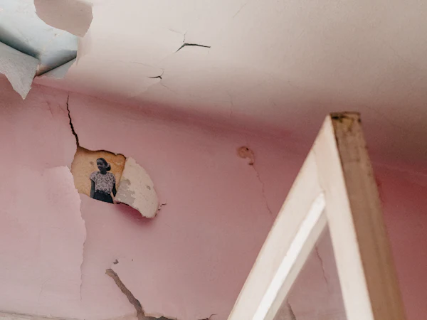 A hole broken through a ceiling after a leak, the old plaster hanging