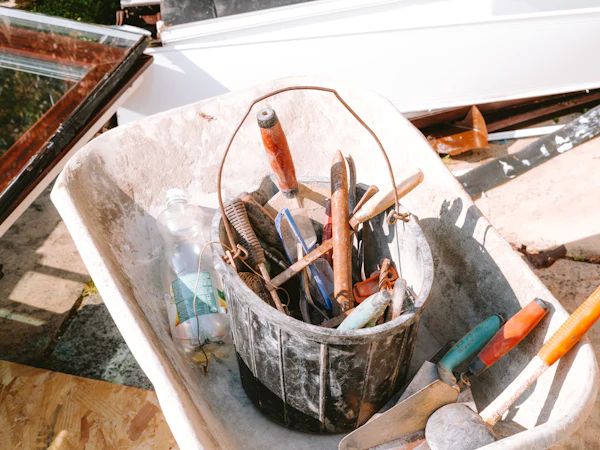 A bucket of trowels, floats and scrapers sitting in a wheelbarrow