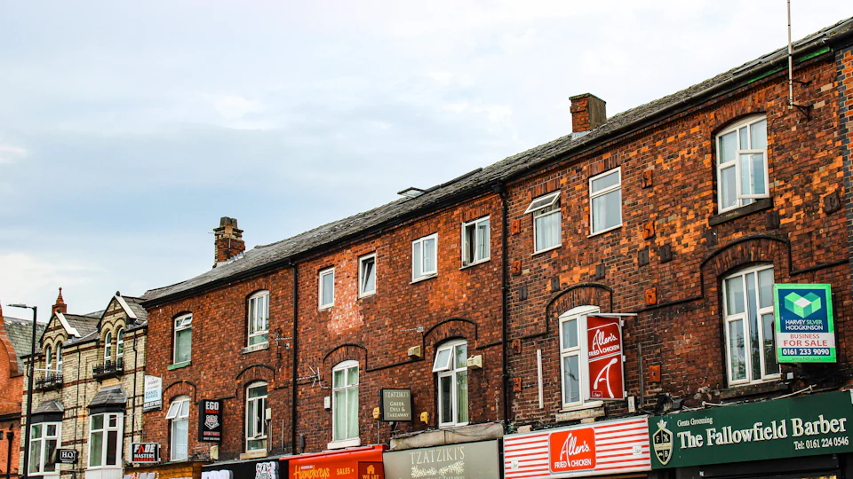 Red-brick terraces above a parade of corner shops in south Manchester