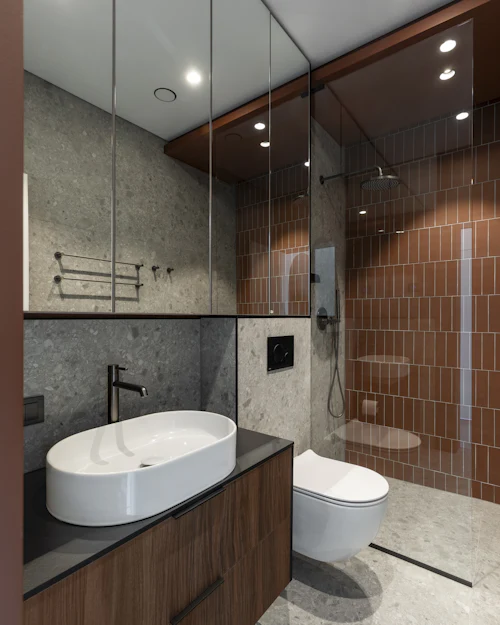 A shower wall in terracotta tiles laid in vertical stack, beside grey stone-look porcelain