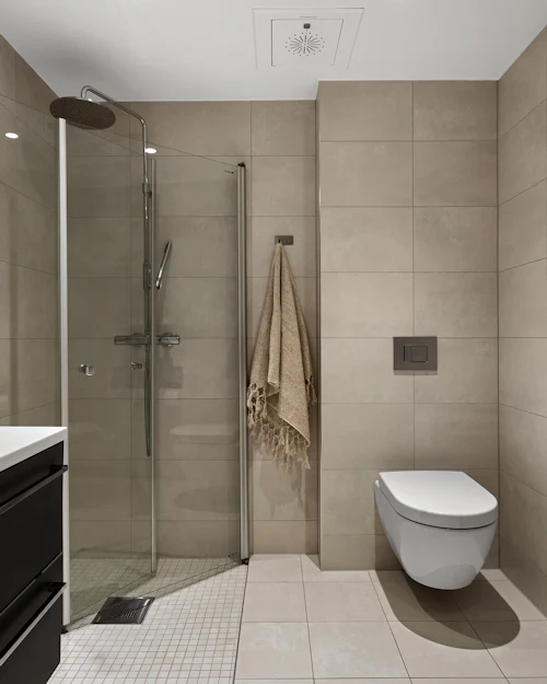 A walk-in shower in large beige porcelain with a wall-hung WC