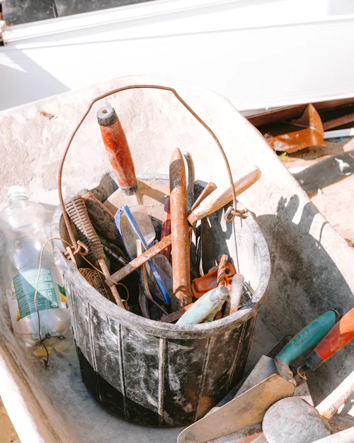 A bucket of hand tools in a wheelbarrow