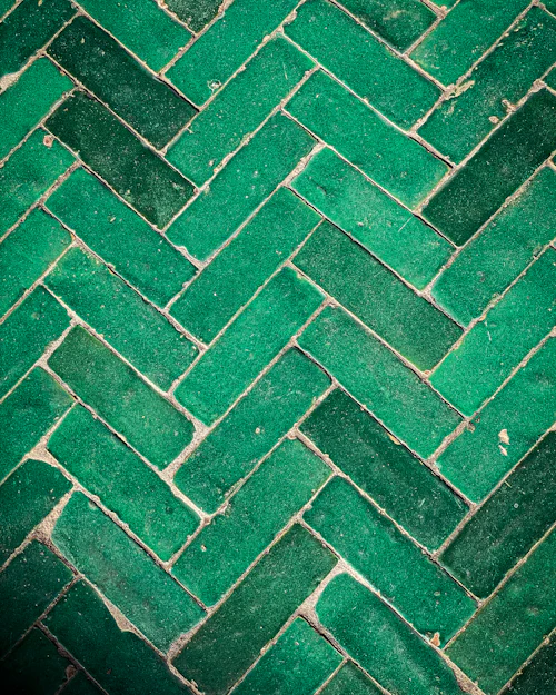 Green handmade zellige tiles laid in herringbone, every glaze a slightly different shade