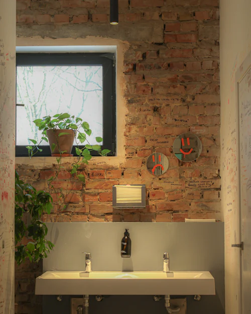 A small shower room with a bare brick wall, a window and a wide basin