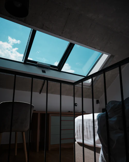 The top of a loft stair under a wide rooflight, with a black metal balustrade