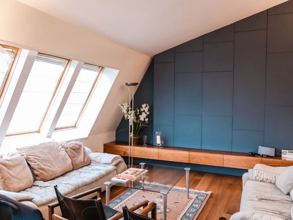 A loft living room with three rooflights in the slope, a sofa and a long low cabinet